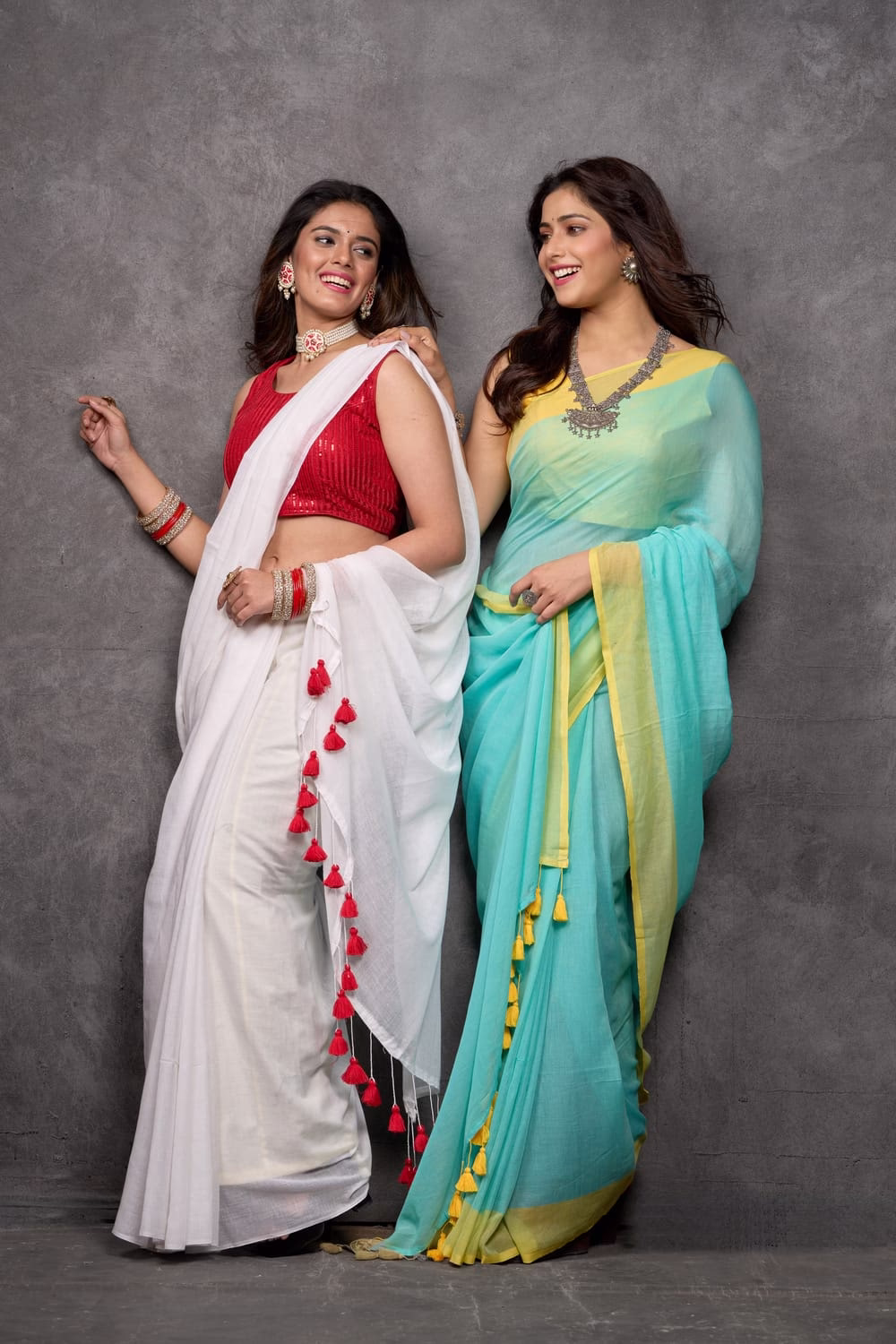 Ivory white mul cotton saree with scarlet red tassels designed by Nikunj Khatri Turquoise blue two dye mul cotton saree with pom pom design by Nikunj Khatri (For combo image) Ivory white and turquoise blue mul cotton sarees side by side designed by Nikunj Khatri